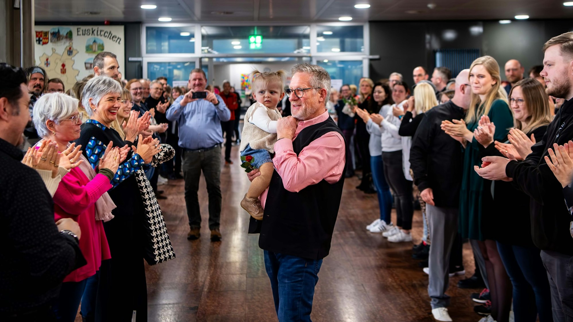 Mit einem Kleinkind auf dem Arm steht Wilfried Krebs zwischen Mitarbeitern der Kreisverwaltung.