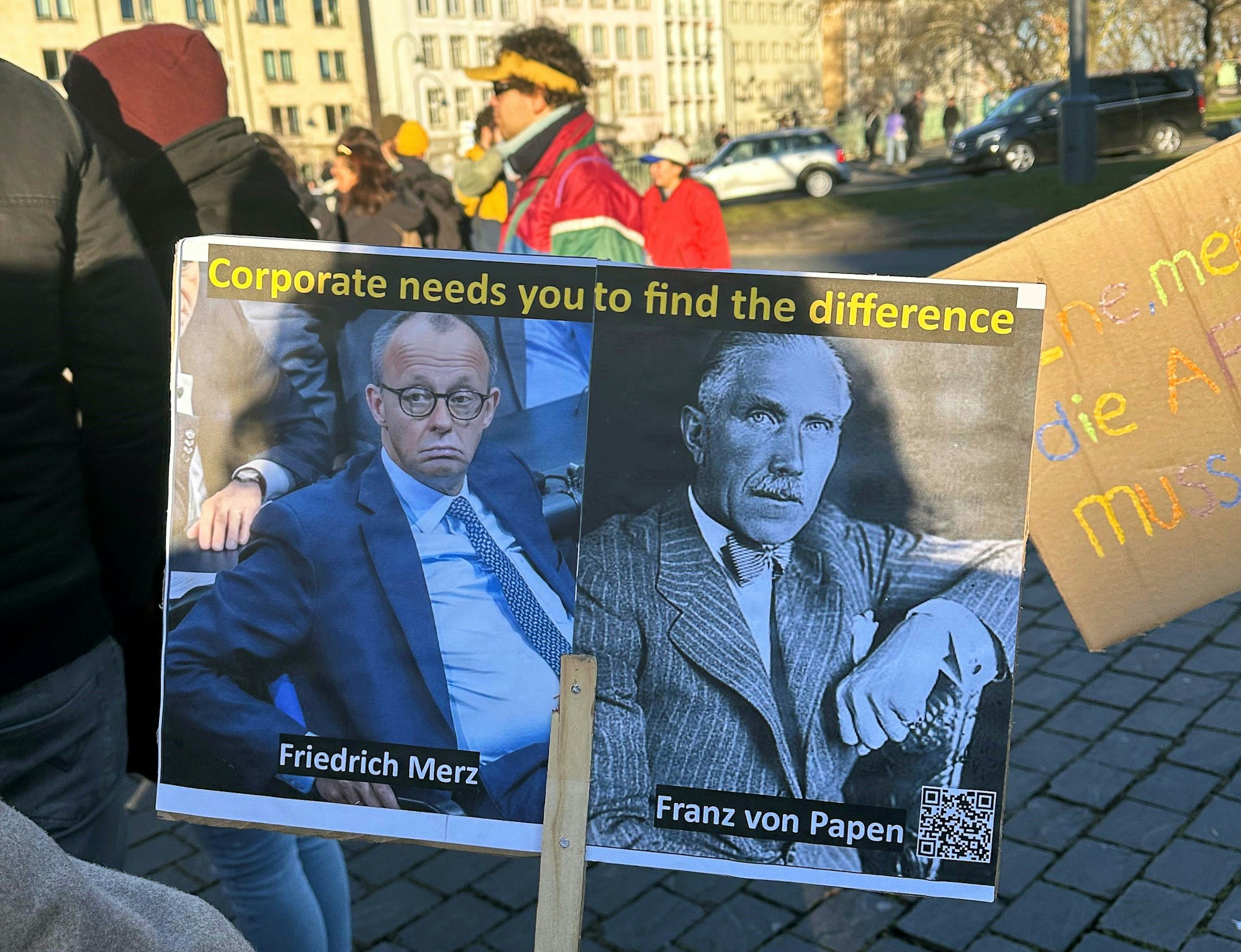 01.01.2025, Nordrhein-Westfalen, Köln: Ein Schild mit dem CDU-Bundesvorsitzenden Merz (l) und dem ehemaligen Reichskanzler Von Papen ist bei einer Demonstration gegen die Migrationspolitik der CDU in der Innenstadt zu sehen. Der Bundestag hatte am Mittwoch mit Unterstützung der AfD einem Antrag der Union zugestimmt, der Zurückweisungen von Asylsuchenden an den deutschen Grenzen vorsieht. Foto: Christoph Driessen/dpa - ACHTUNG: Nur zur redaktionellen Verwendung im Zusammenhang mit der aktuellen Berichterstattung und nur mit vollständiger Nennung des vorstehenden Credits +++ dpa-Bildfunk +++