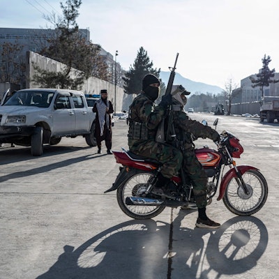 Taliban security personnel ride past the former US Embassy building in Kabul