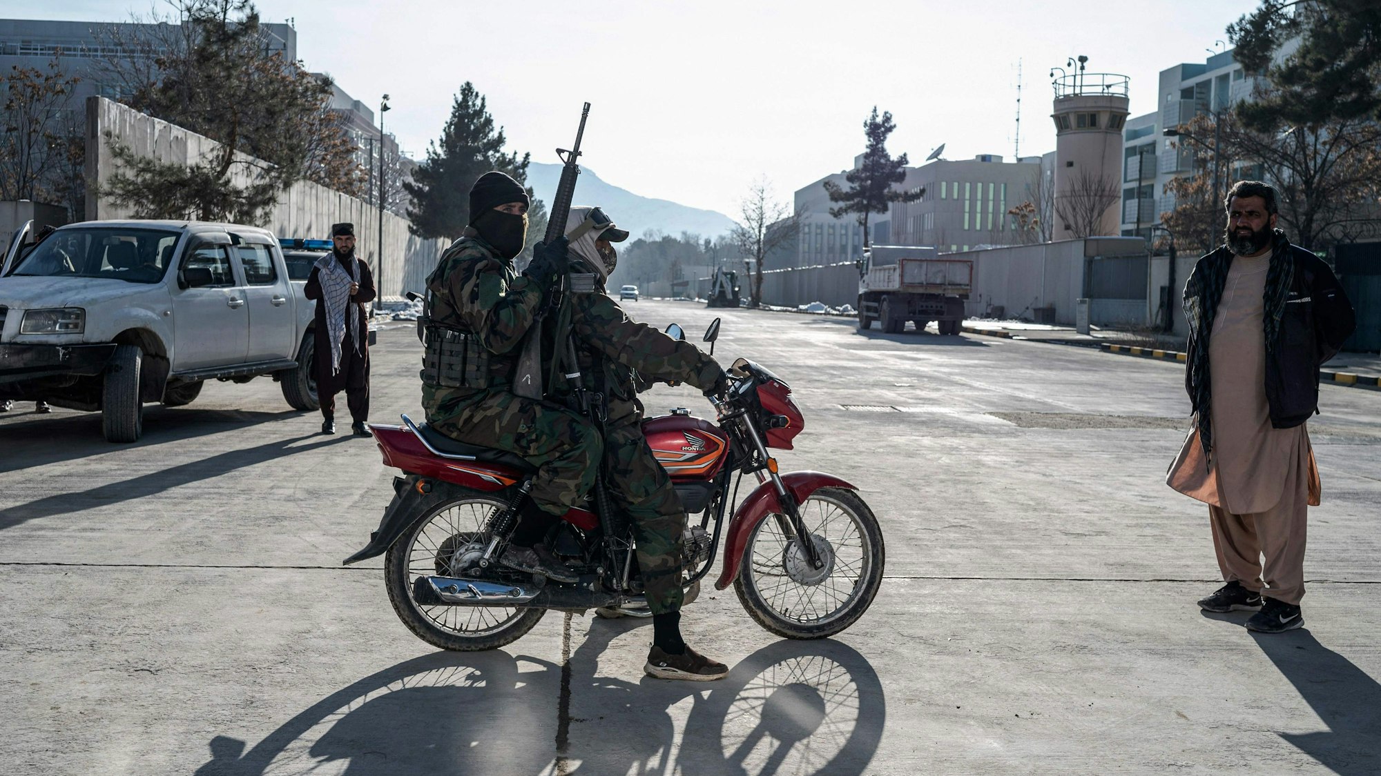 Taliban security personnel ride past the former US Embassy building in Kabul