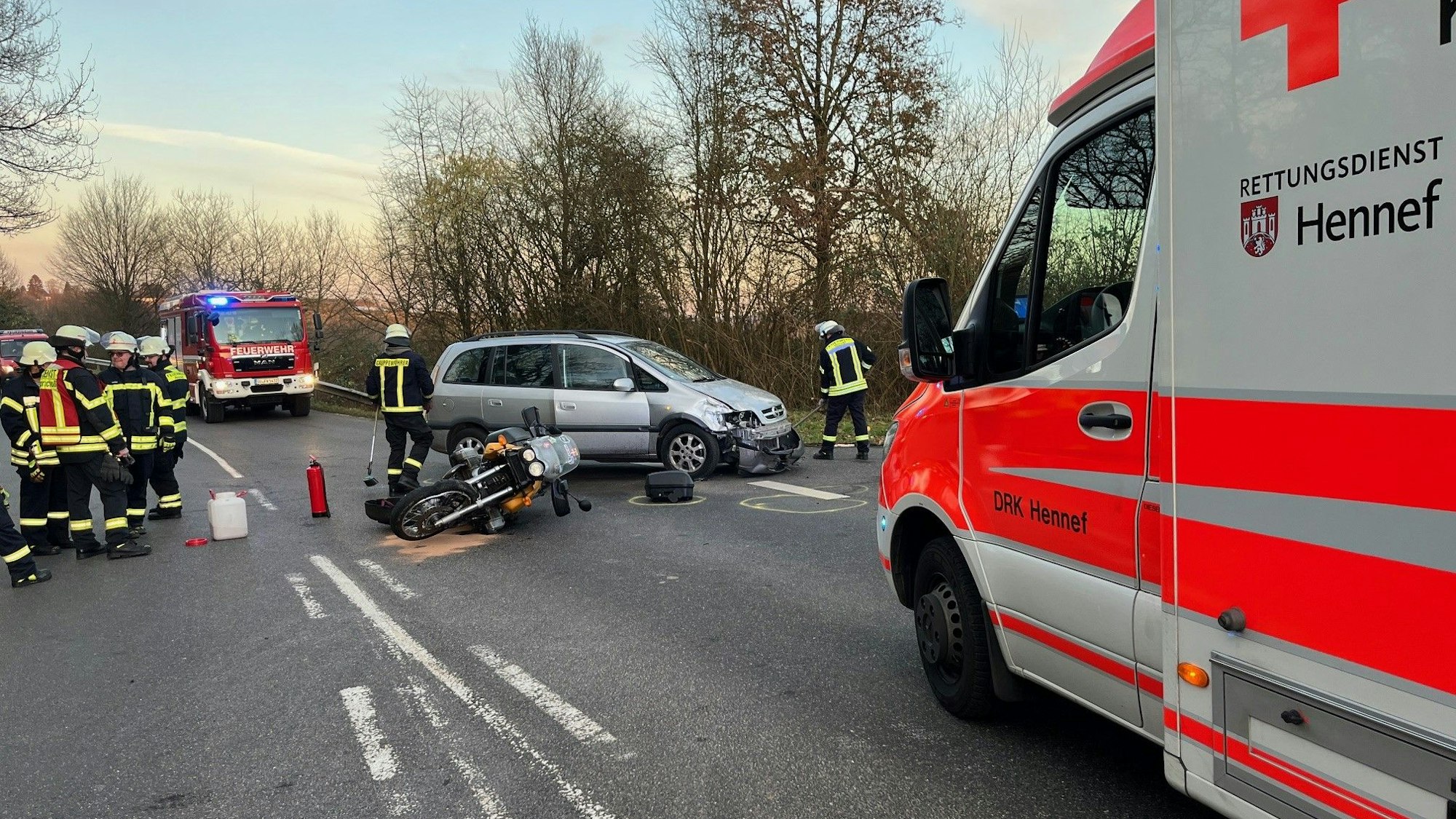 Ein umgestürztes Motorrad liegt vor einem beschädigten Auto und neben einem Rettungswagen.