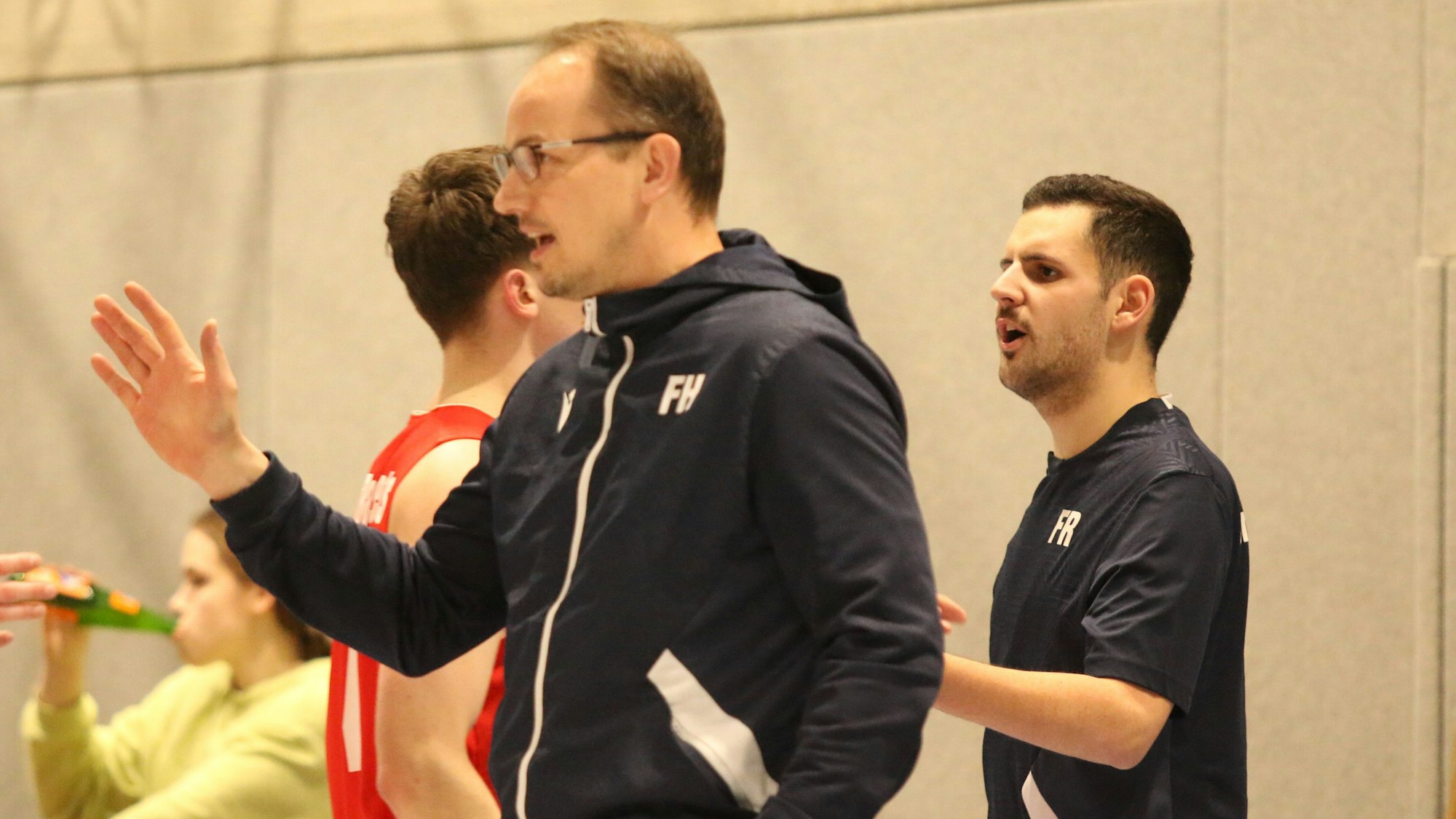 Trainer Florian Hammes hat eine Hand in der Tasche und gibt mit der anderen Anweisungen.