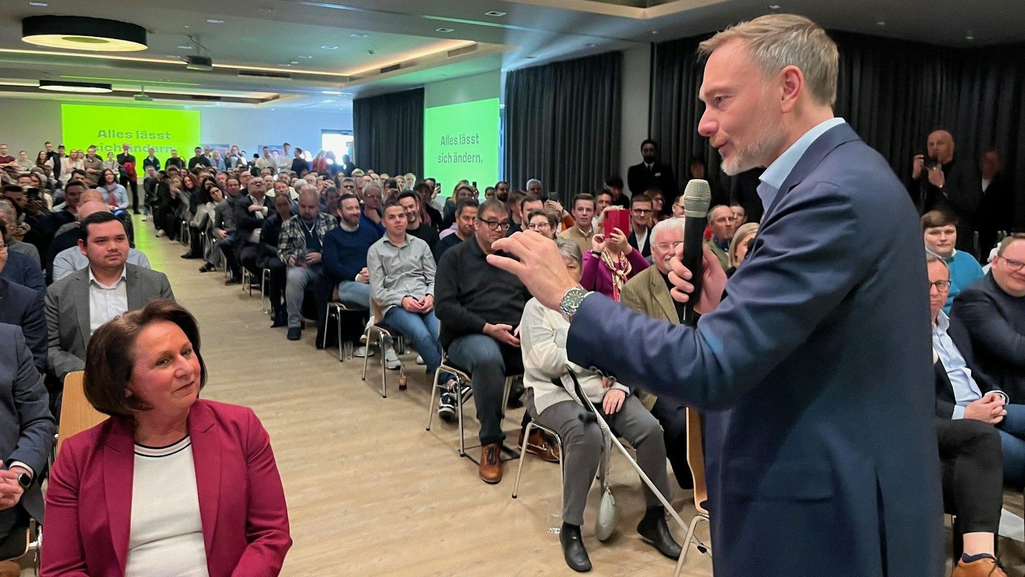 Ein Mann spricht vor vielen Zuschauern in ein Mikrofon.