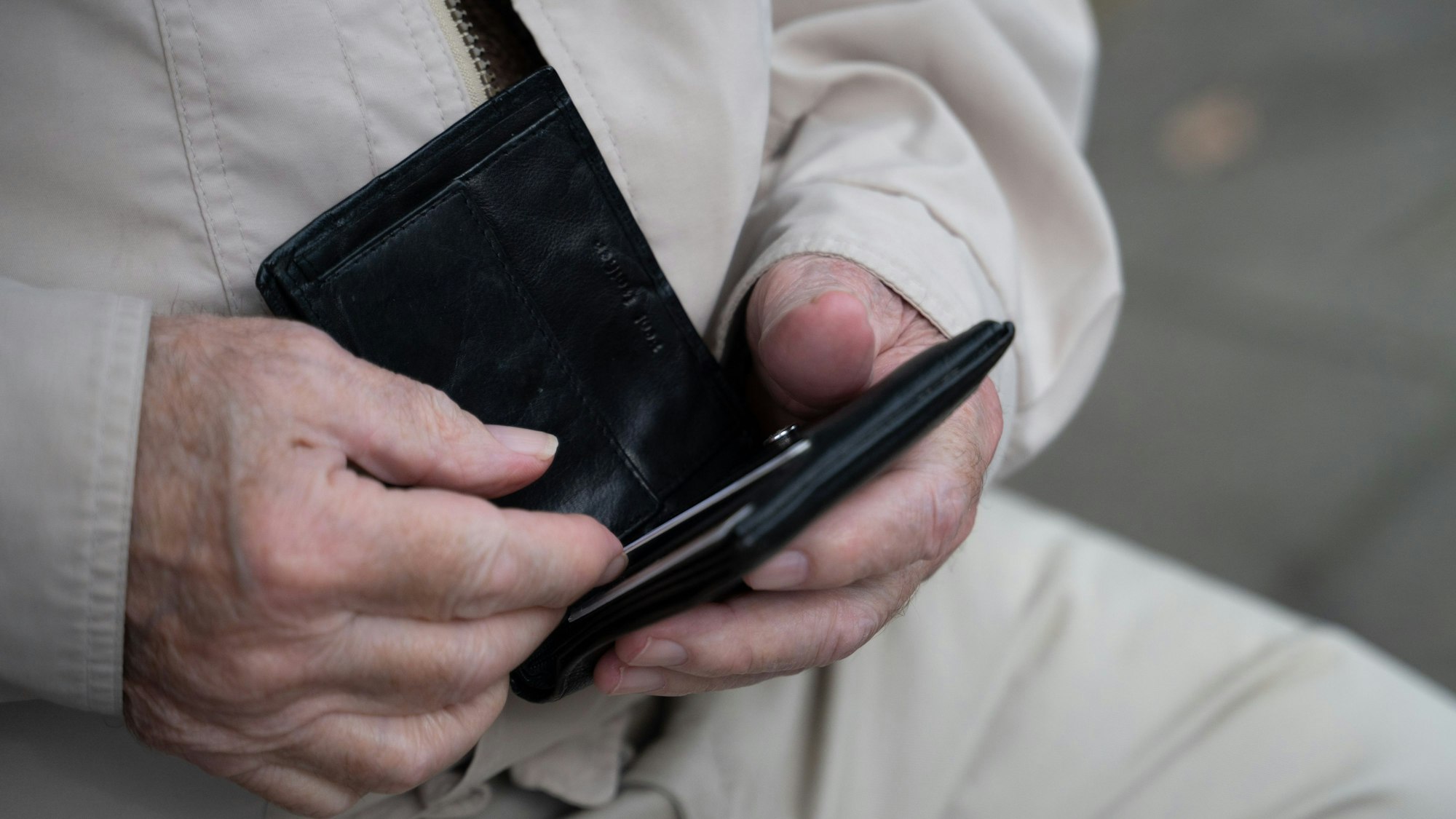 Ein Rentner hält sein Portemonnaie in der Hand.