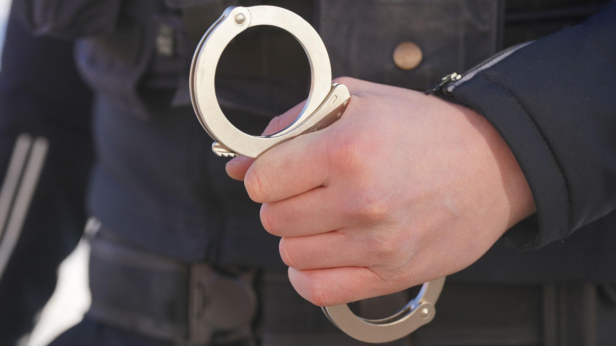 Ein Polizist hält Handschellen in der Hand. In NRW können aktuell rund 28000 Haftbefehle nicht vollstreckt werden.