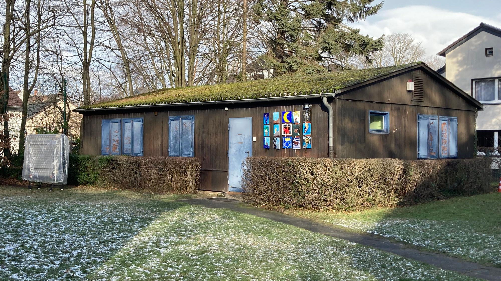 Ein braunes Blockhaus mit blauen Fensterläden und Türen.