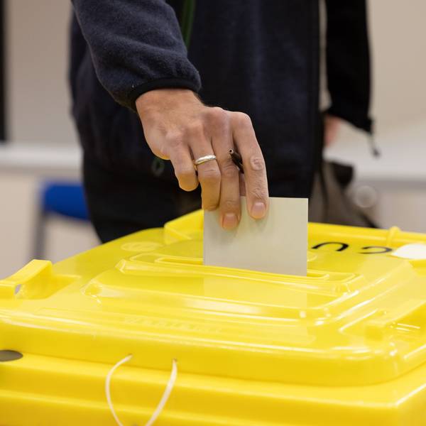 Eine Person wirft einen Umschlag in eine Wahlurne. (Symbolbild)