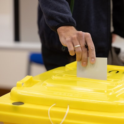 Eine Person wirft einen Umschlag in eine Wahlurne. (Symbolbild)