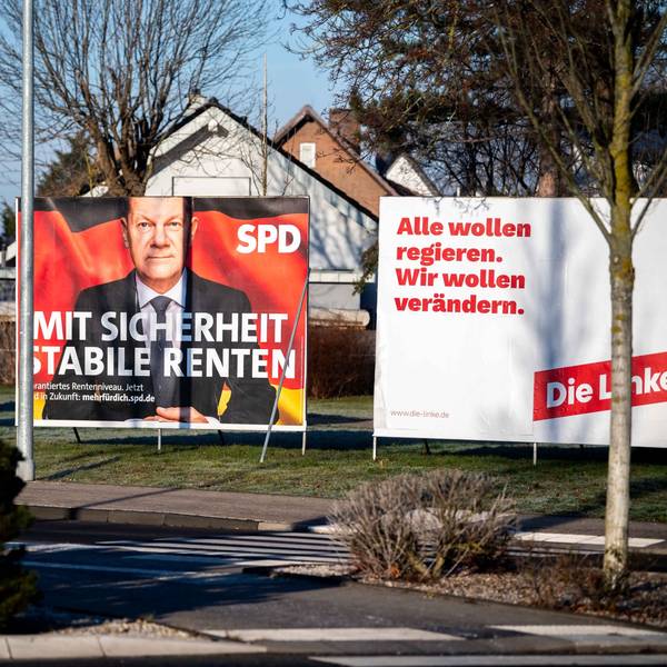 Mehrere Ständer mit Wahlplakaten stehen nebeneinander an einer Grünfläche.
