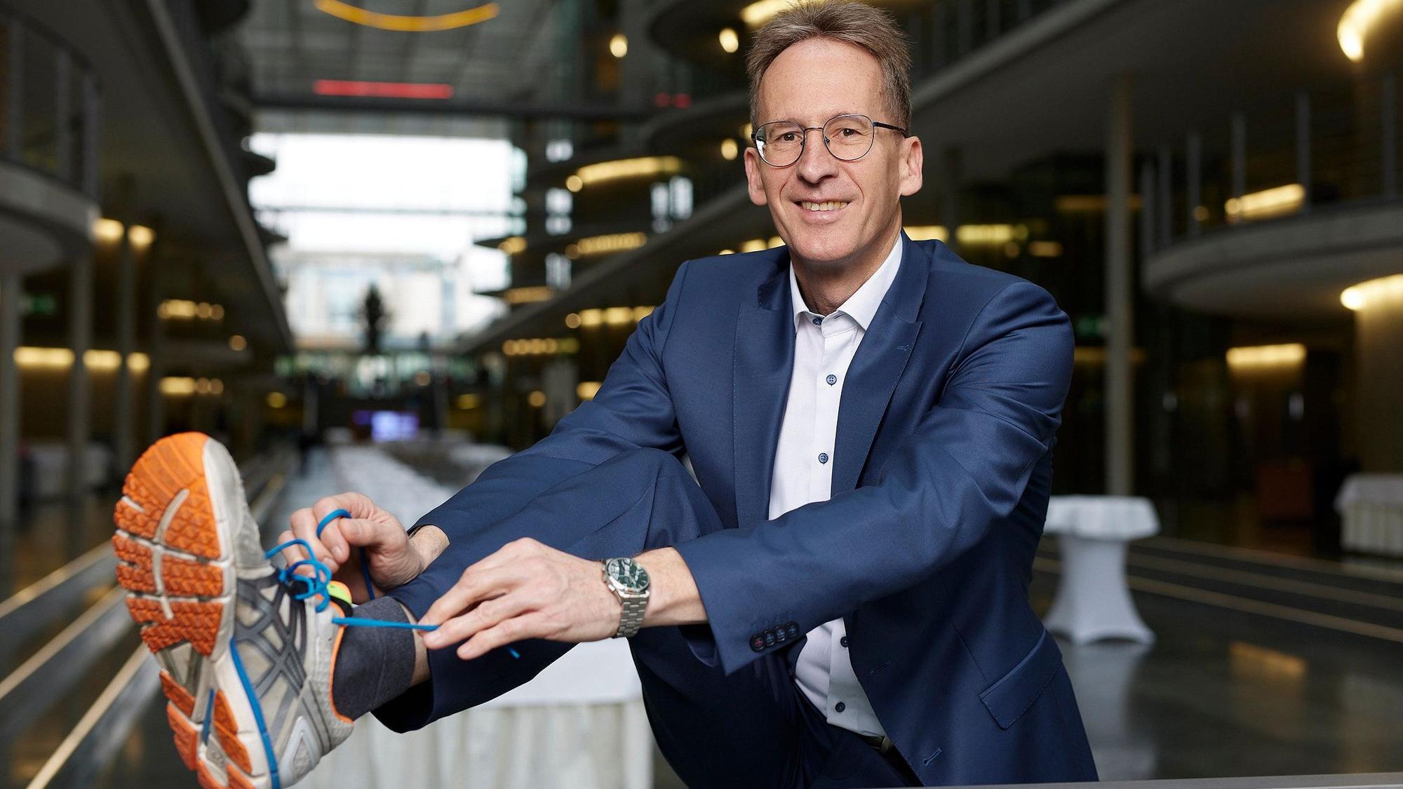 Das Foto zeigt den CDU-Bundestagsabgeordneten Detlef Seif. Er trägt einen Anzug und bindet sich einen Joggingschuh zu.