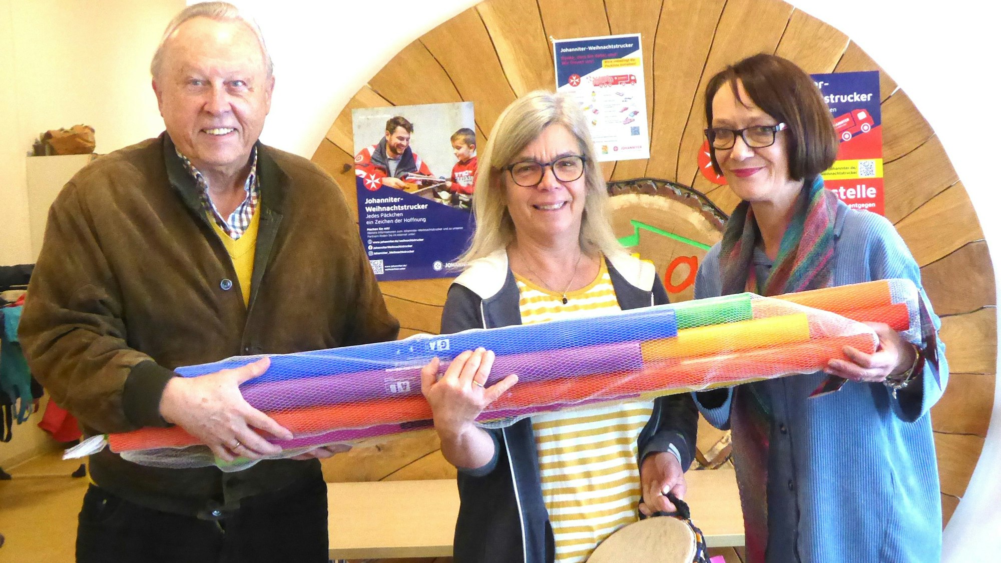 Das Foto zeigt drei Personen bei der Übergabe von Instrumenten.