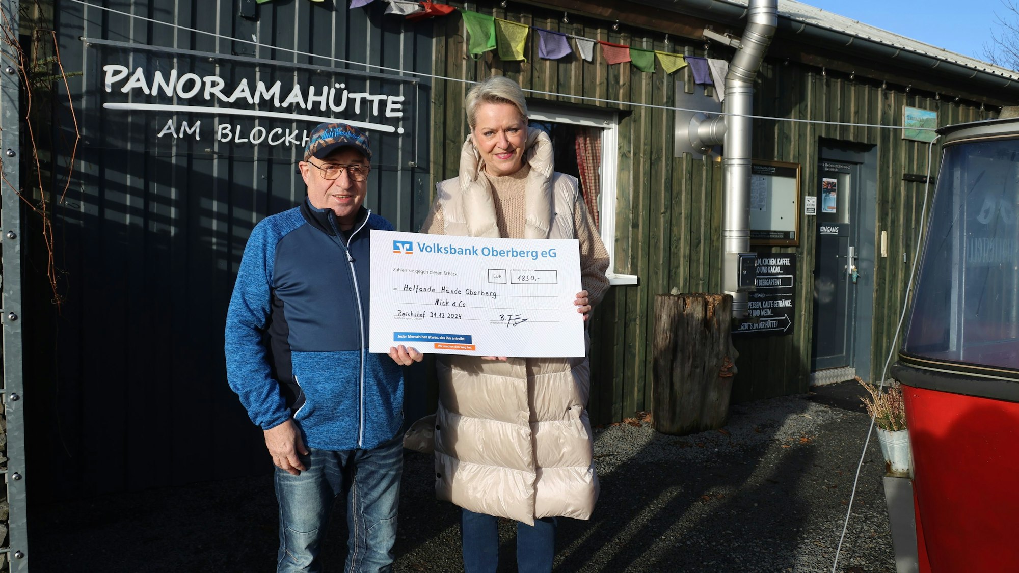 Bernhard Junge übergibt vor der Panoramahütte am Blockhaus eine Spende an Bettina Hühn.