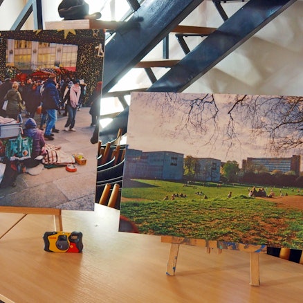 Auf Staffeleien stehen zwei Bilder, die Szenen in Köln zeigen.