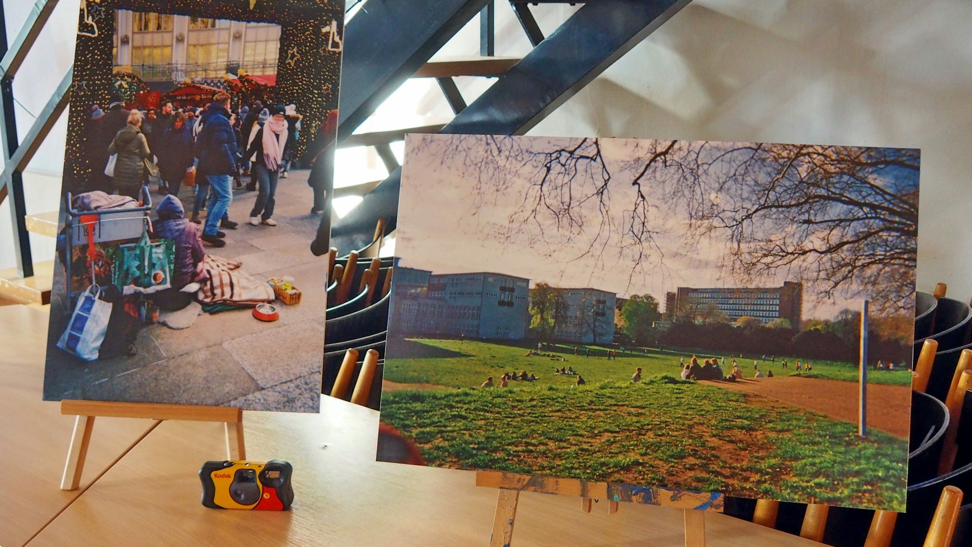 Auf Staffeleien stehen zwei Bilder, die Szenen in Köln zeigen.