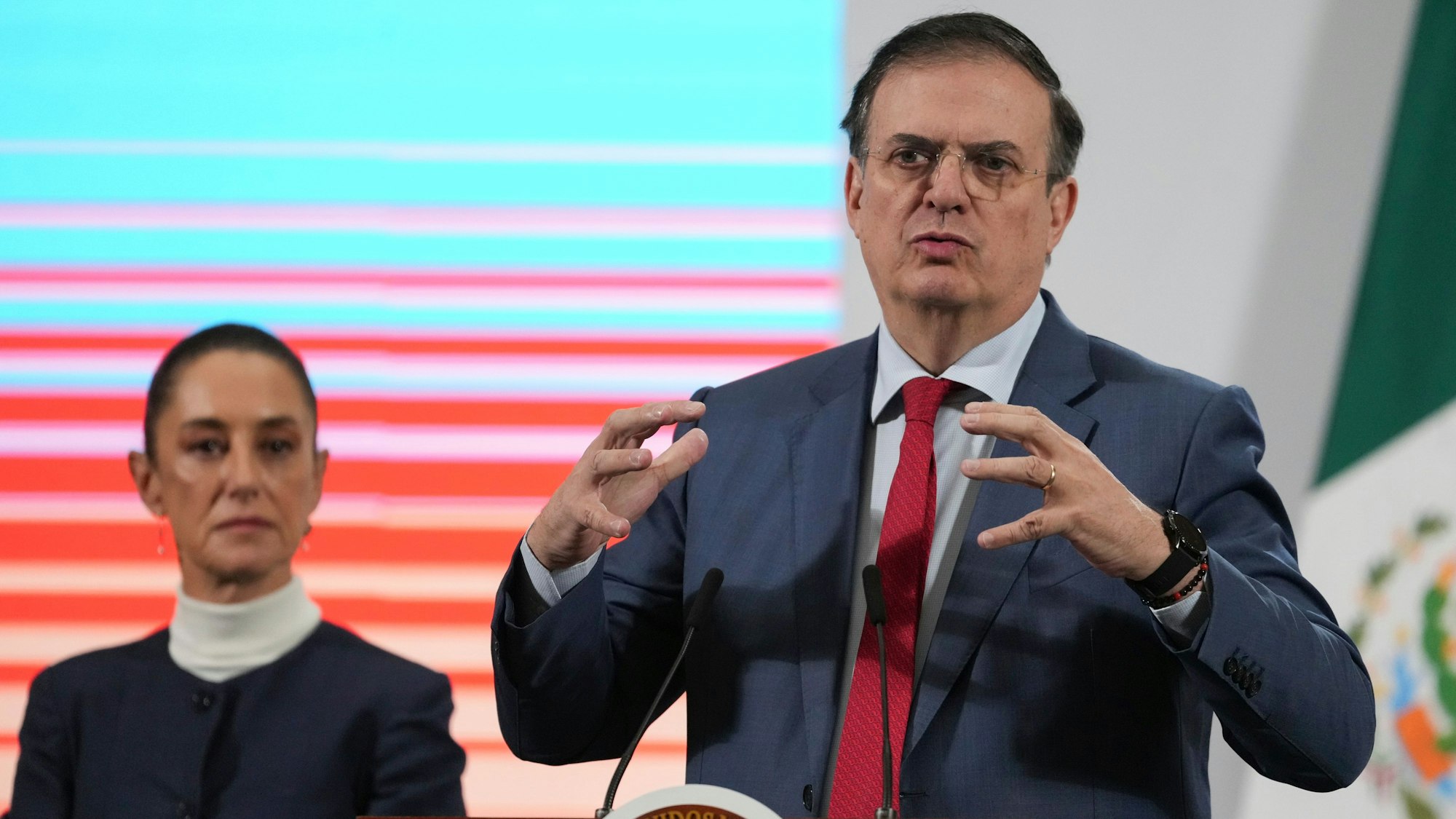 Der mexikanische Wirtschaftsminister Marcelo Ebrard auf der täglichen morgendlichen Pressekonferenz der Präsidentin Claudia Sheinbaum (l) im Nationalpalast in Mexiko-Stadt. Die USA setzen die angekündigten Zölle gegen Mexiko nach Angaben der mexikanischen Präsidentin Claudia Sheinbaum vorerst aus.