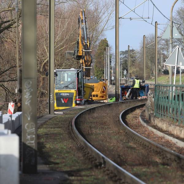 Große Betonklötze stehen neben einer Stadtbahntrasse, im Hintergrund stehen Baumaschinen
