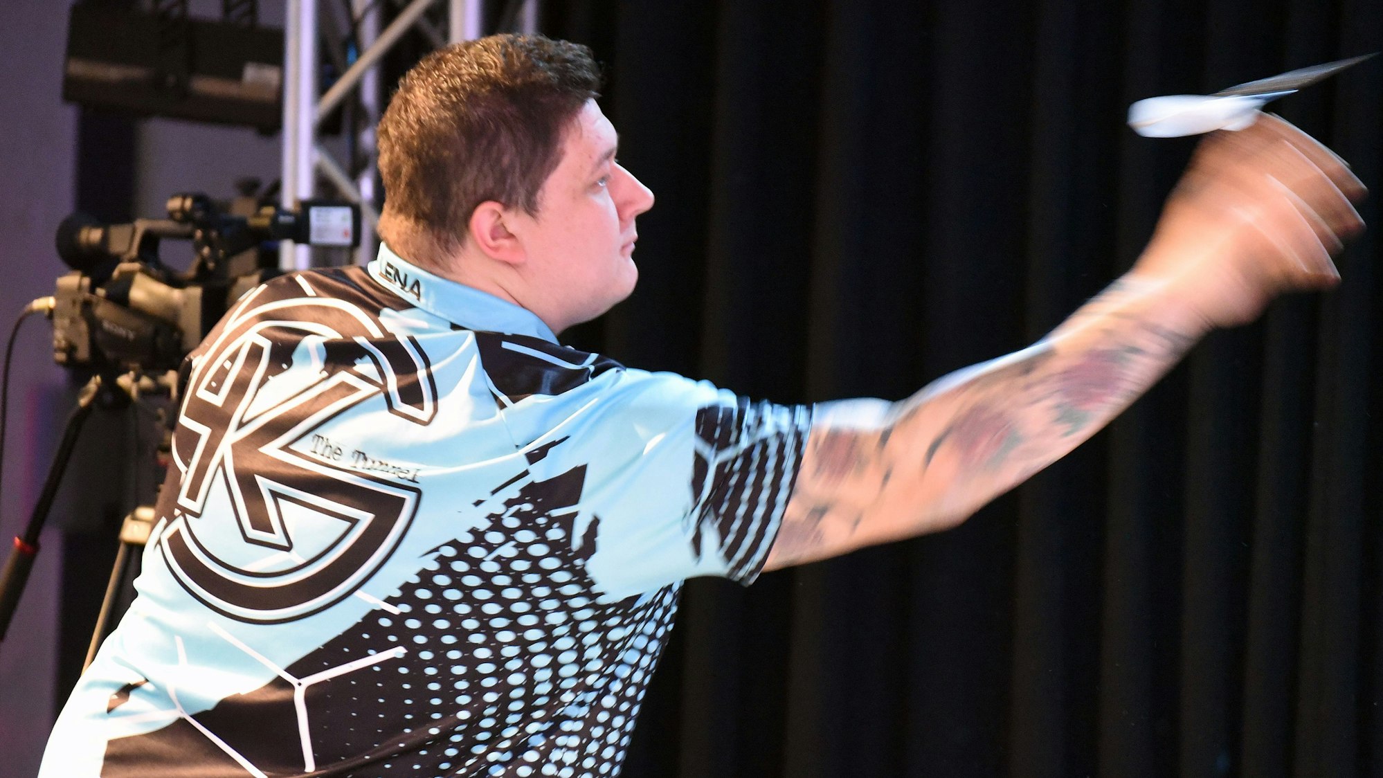 Bild eines Dartspielers, der einen Pfeil wirft.