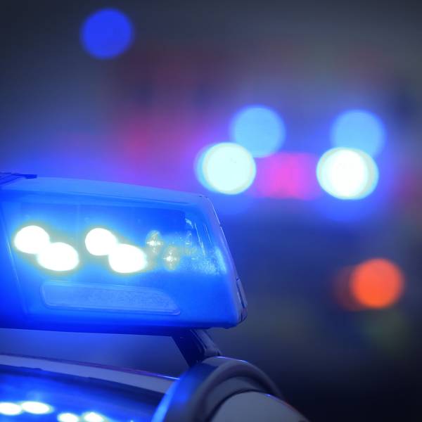 Ein Polizeiauto bei Dunkelheit mit eingeschaltetem Blaulicht