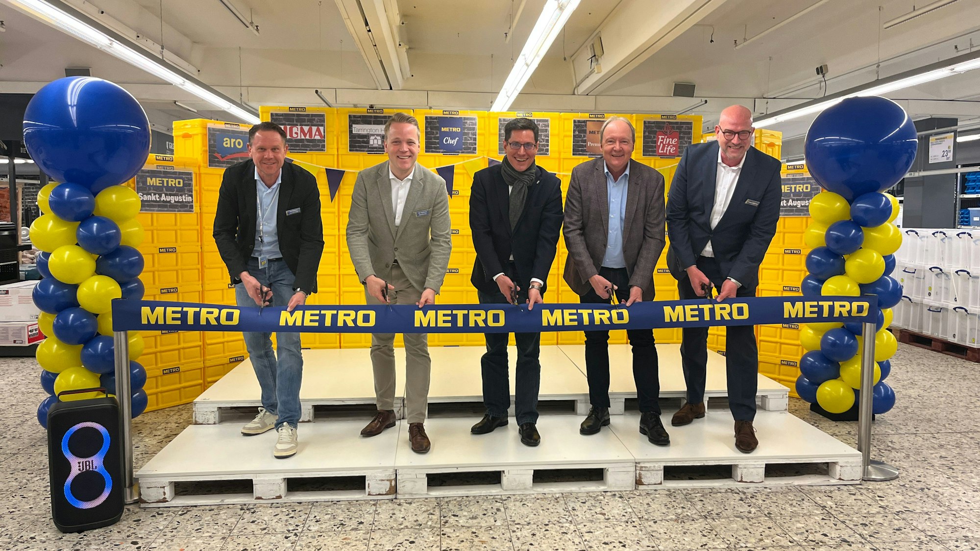 Fünf Männer durchschneiden ein blaues Band mit der Aufschrift Metro.