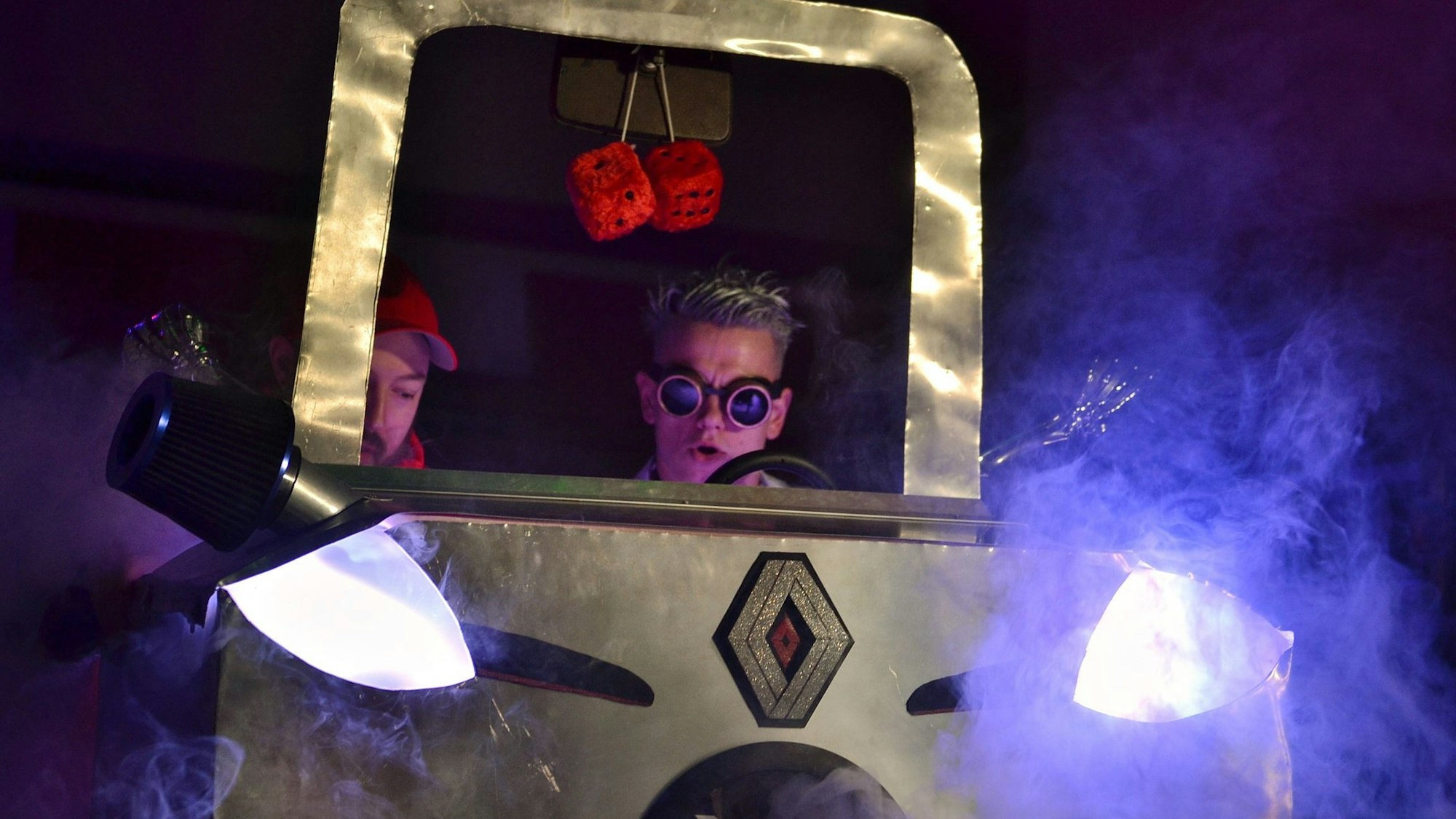 Zwei Mitglieder der Gruppe Magic Men sitzen in einem selbstgebauten Auto.