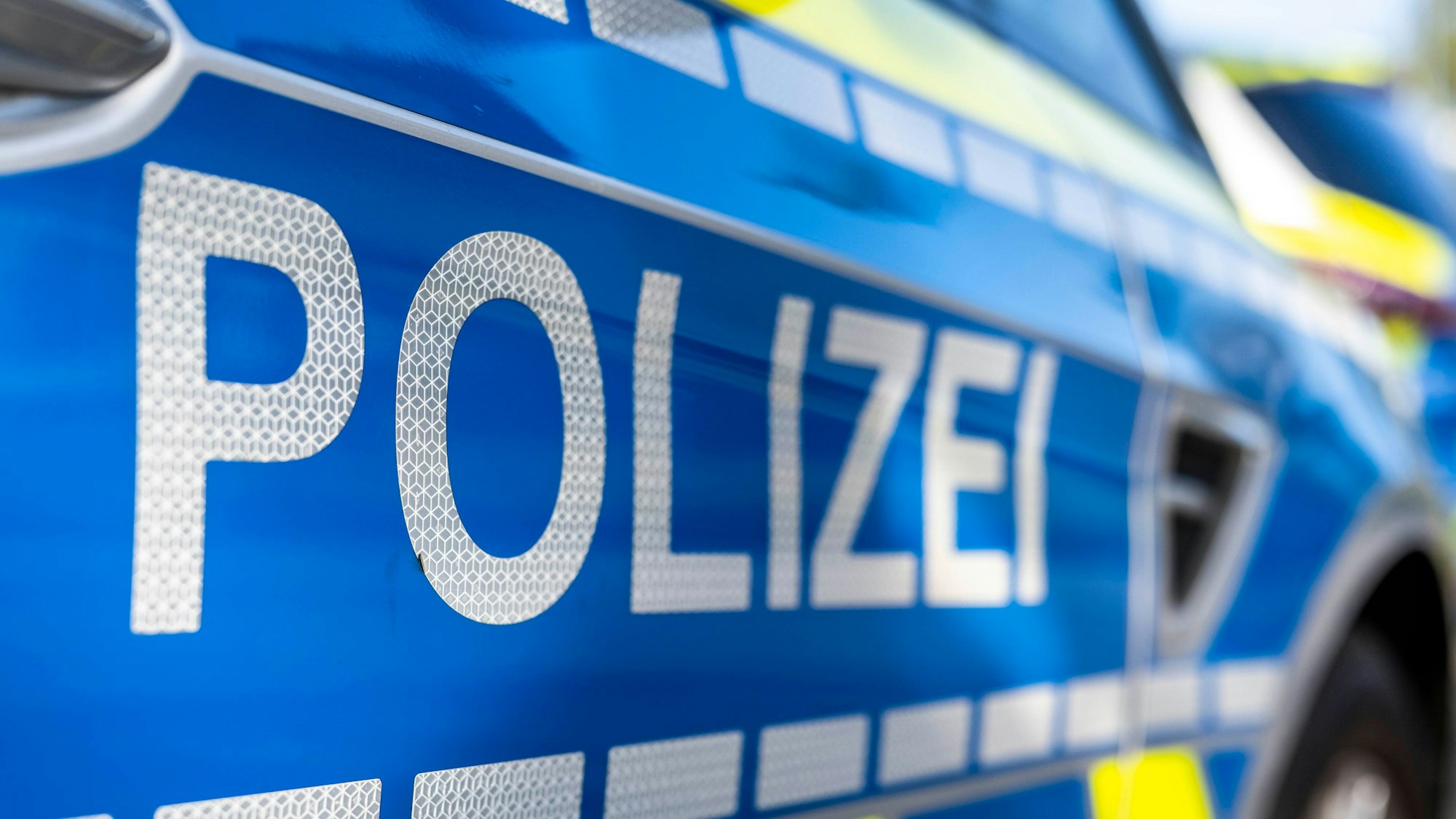 An der Tür von einem Streifenwagen steht der Schriftzug „Polizei“