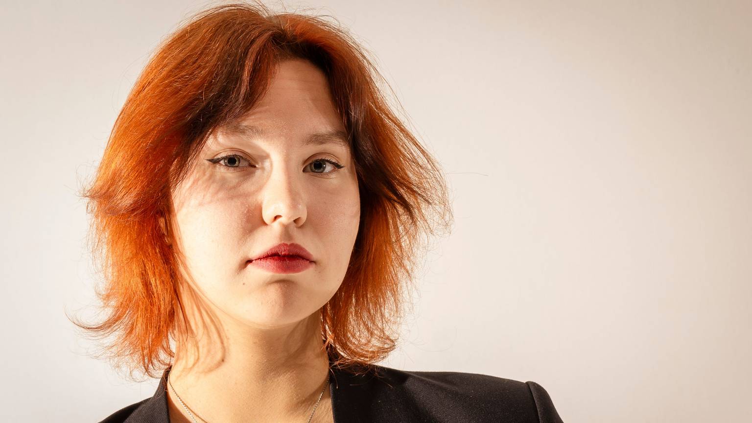 Katharina Zenses
ist im Porträt zu sehen. Sie hat gestuftes rotes Haar und blickt in ernst die Kamera.