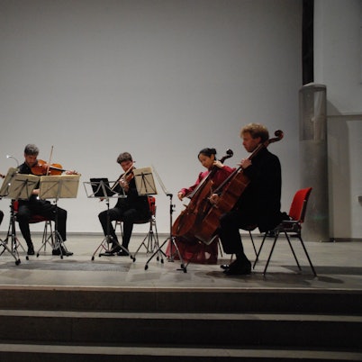 Auf der Bühne sitzen im Halbkreis sechs Streicher und musizieren.