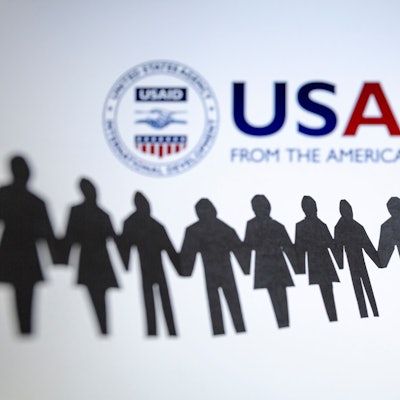 Das Logo der US-Entwicklungsbehörde, United States Agency for International Development (USAID), ist hinter einer Kette von ausgeschnittenen Papierfiguren zu sehen.