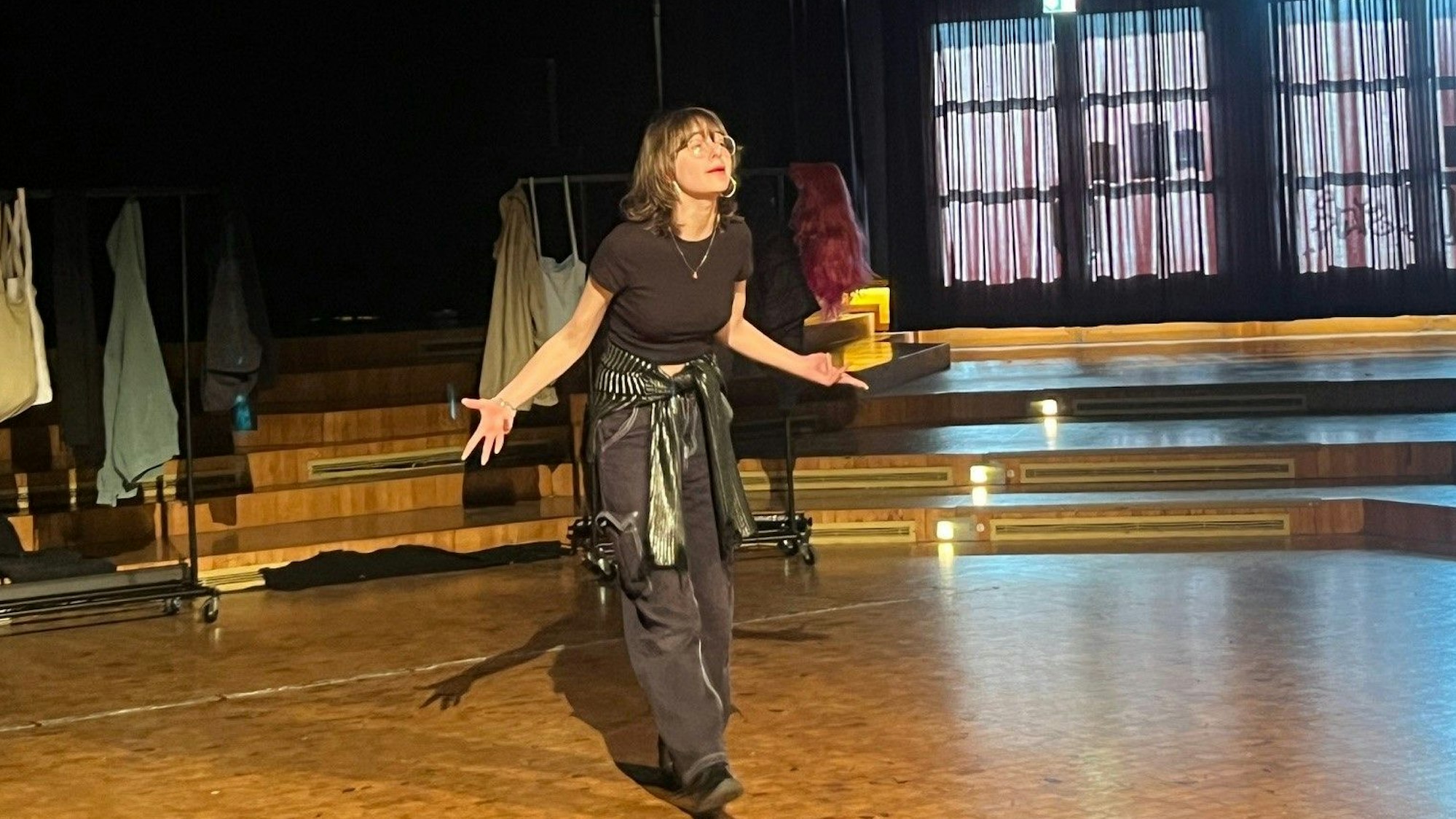 Eine junge Frau steht auf einer Bühne und spricht ins Publikum.