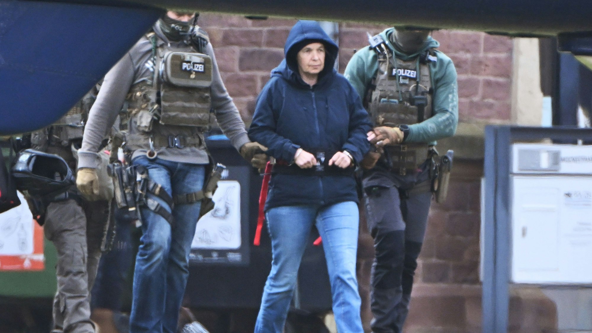 Im Innenhof eines Behördenzentrums wird die frühere RAF-Terroristin Daniela Klette zu einem Hubschrauber geführt.
