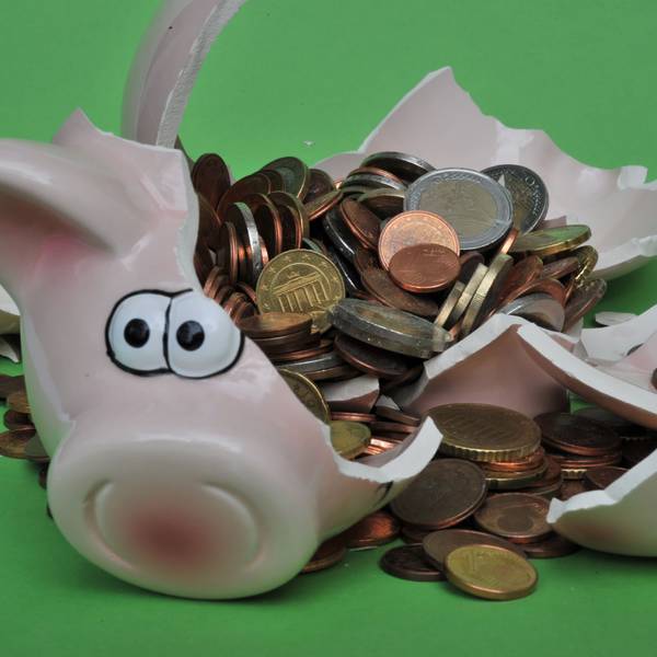 Ein Sparschwein mit Euro-Geldstücken liegt zerbrochen auf einem Tisch.