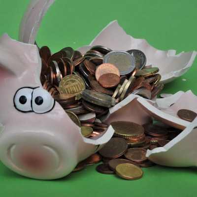 Ein Sparschwein mit Euro-Geldstücken liegt zerbrochen auf einem Tisch.