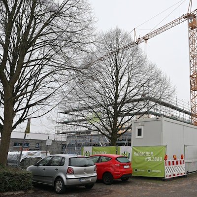 Ein großer gelber Baukran ragt über den eingezäunten Rohbau.
