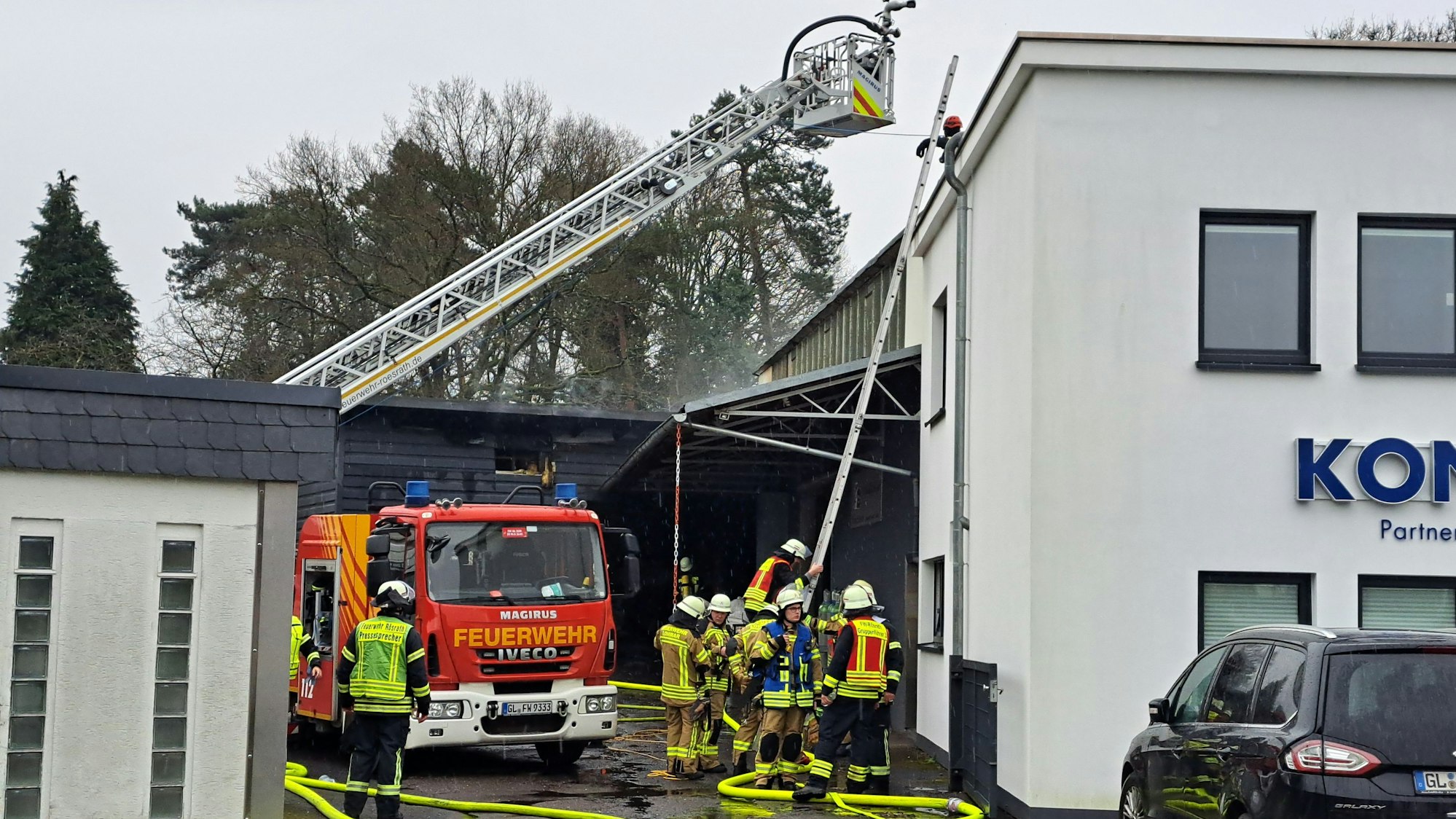 Die Feuerwehr löscht mit einer Drehleiter einen Gewerbehallenbrand in Rösrath.