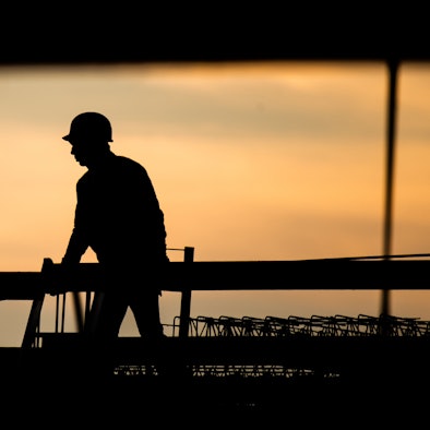 ARCHIV - 31.08.2021, Niedersachsen, Hannover: Die Silhouette eines Bauarbeiters zeichnet sich auf einer Baustelle vor dem verfärbten Morgenhimmel ab.  Der Fachkräftemangel in Deutschland wirkt sich negativ auf den Arbeitsalltag und die Zufriedenheit vieler Beschäftigter aus. (zu dpa: «Mehr Beschäftigte in Berlin - Weniger in Brandenburg») Foto: Julian Stratenschulte/dpa +++ dpa-Bildfunk +++