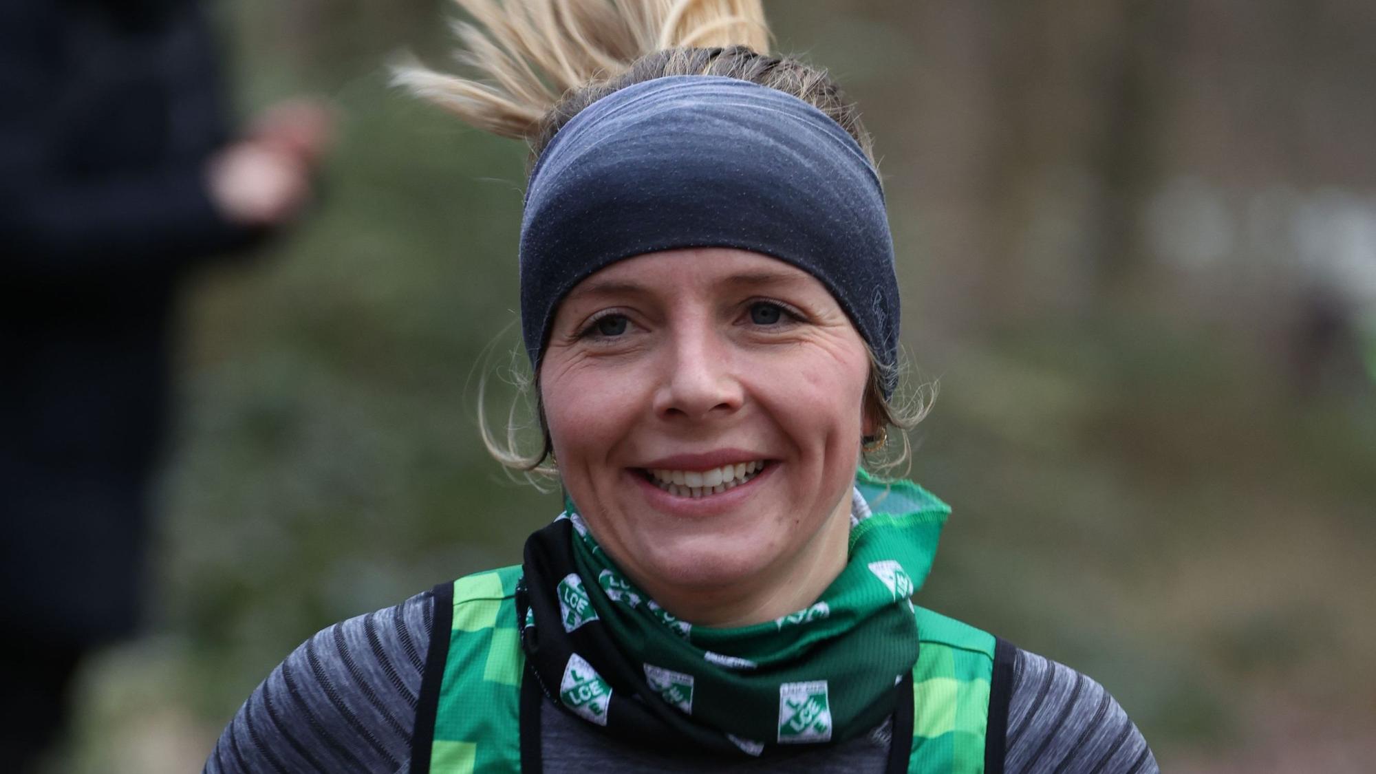 Nora Schmitz trägt beim Laufen ein Stirnband, das auch die Ohren bedeckt. Ihr blonder Zopf fliegt in die Höhe. Sie lächelt.