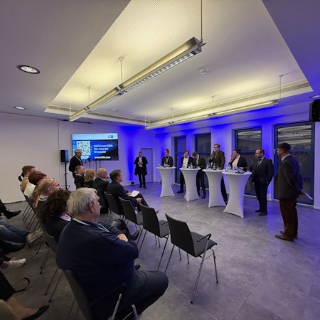 Nyke Slawik, Tomás Santillán, Karl Lauterbach, Rolf Albach, Caroline Bosbach und Harald Weyel stehen an Tischen in der Opladener IHK