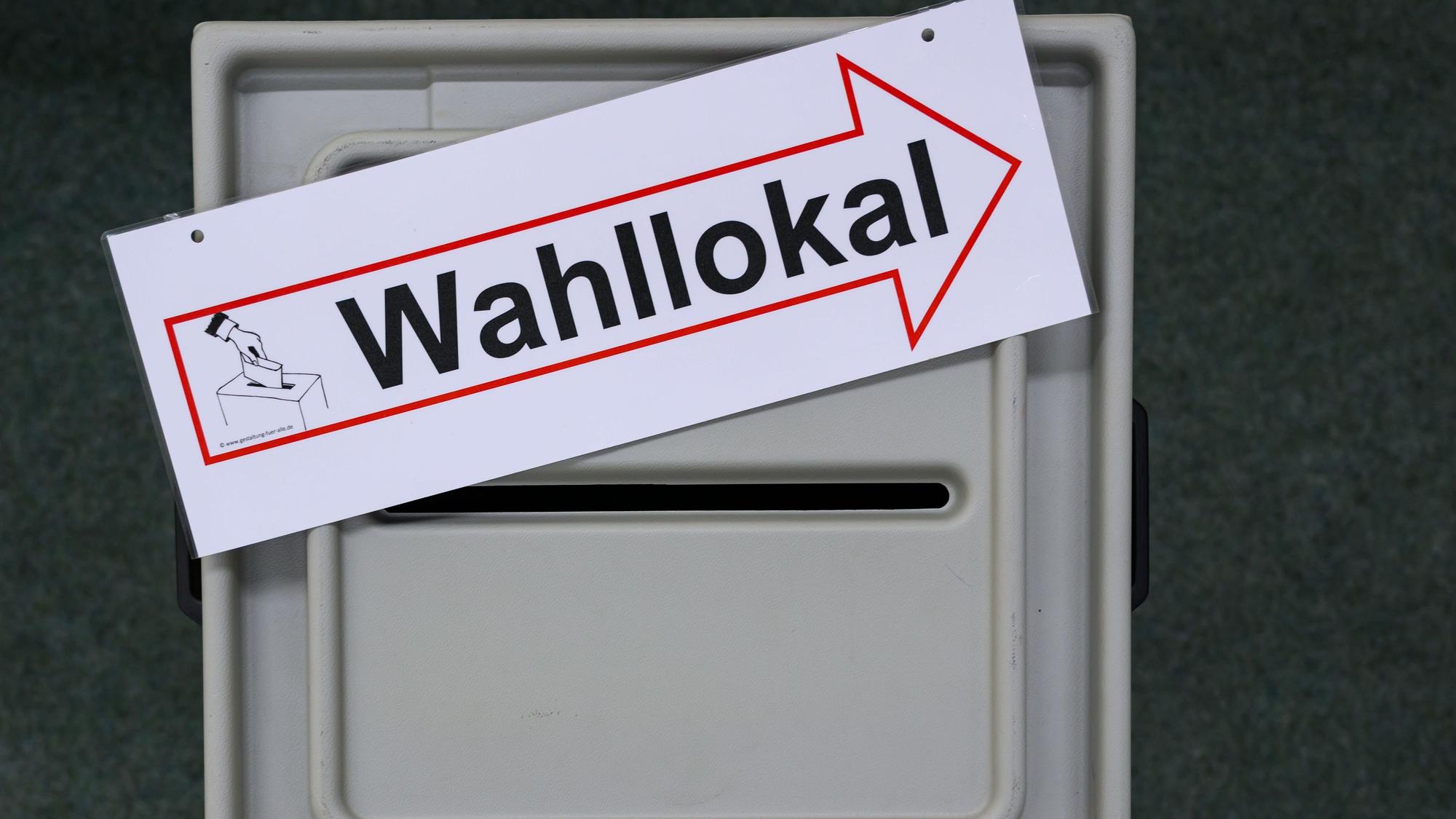 Ein Schild mit der Aufschrift Wahllokal liegt auf einer Wahlurne.