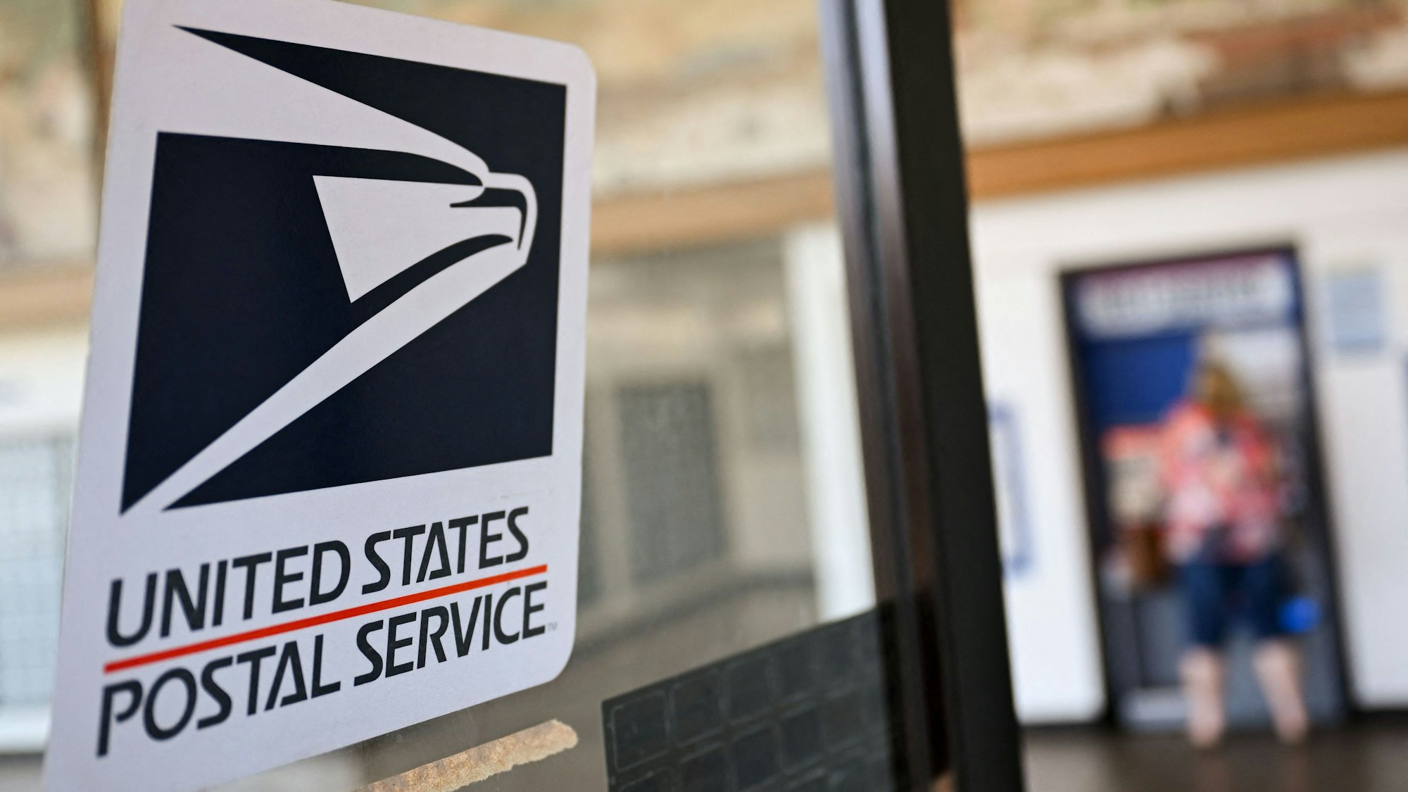 Ein Sticker mit dem Logo der Postbehörde USPS klebt auf einer Scheibe
