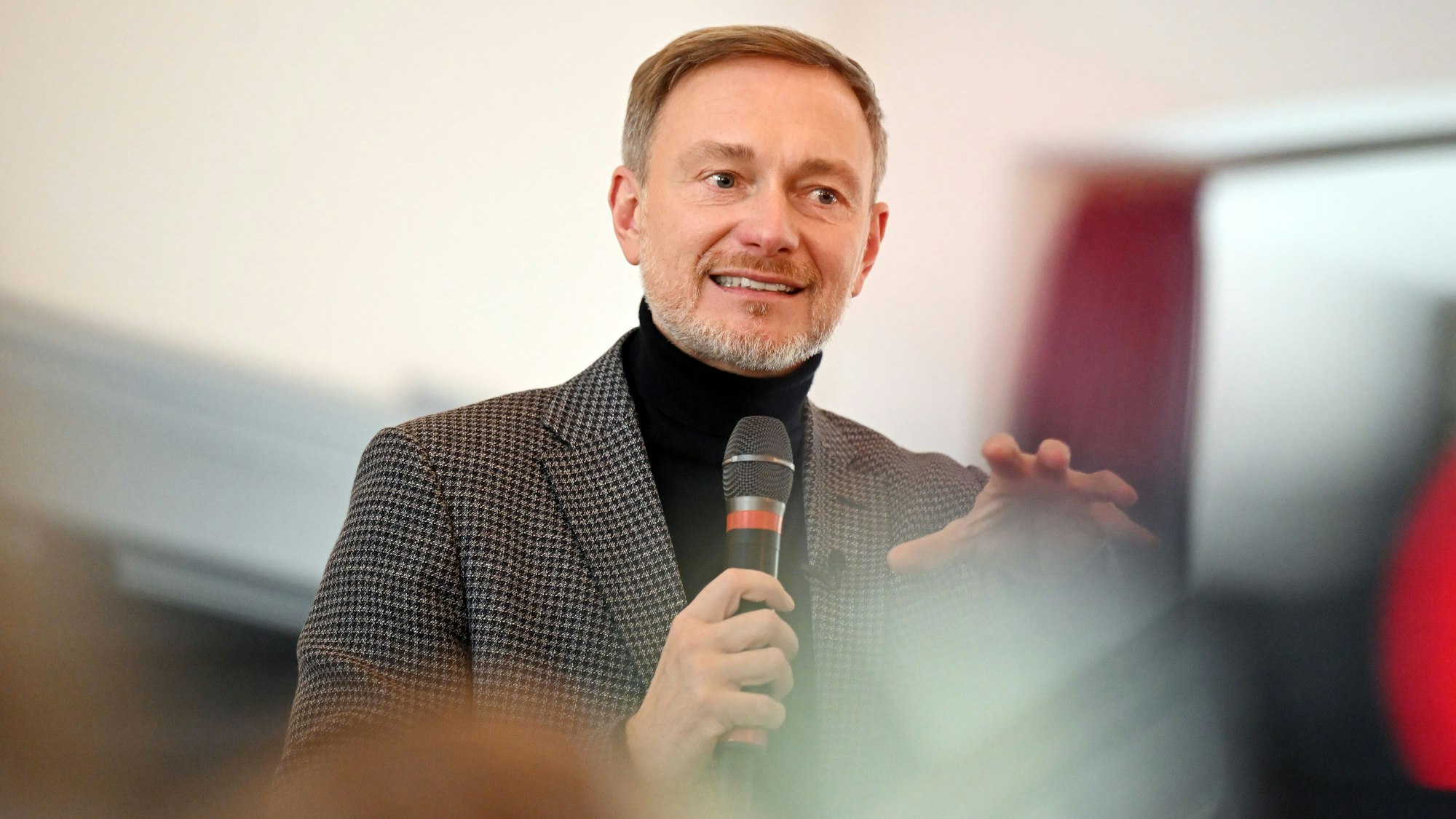 Christian Lindner hält ein Mikrofon in der Hand und spricht.