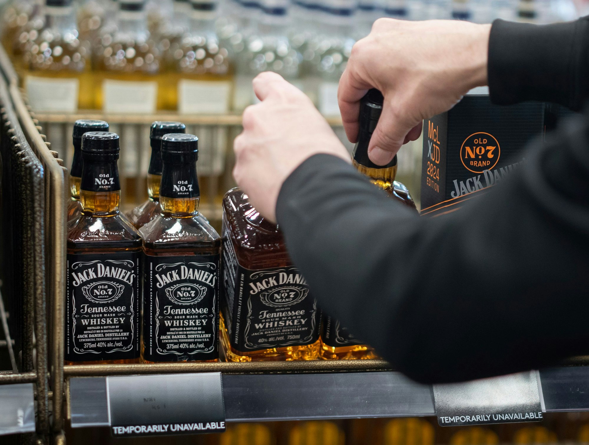 Ein Angestellter des B.C. Liquor Store in Kanada demonstriert den Medienvertretern vor einer Pressekonferenz, wie Flaschen mit amerikanischem Whiskey entfernt werden.