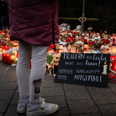 Ein Kind steht an einer Gedenkstätte in Aschaffenburg. Auf einem Schild steht „weniger Wahlkampf, mehr Mitgefühl“. (Archivbild)