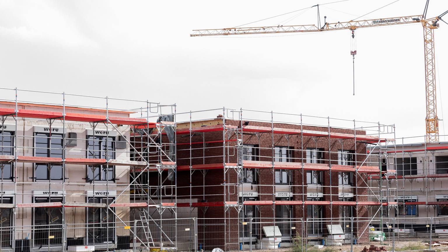 Häuser stehen eingerüstet auf einem Baufeld am Stadtrand von Köln.