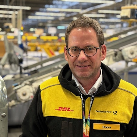 Auf dem Bild ist der neue Leiter der DHL-Niederlassung Betrieb Köln-West in einem Verteilzentrum zu sehen.