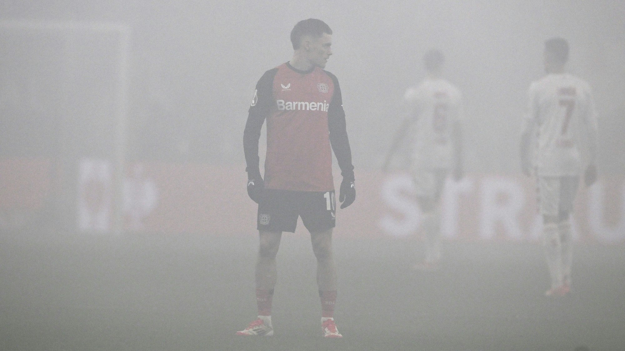 Florian Wirtz steht in der Bay-Arena im Rauch von Pyrotechnik auf dem Platz.