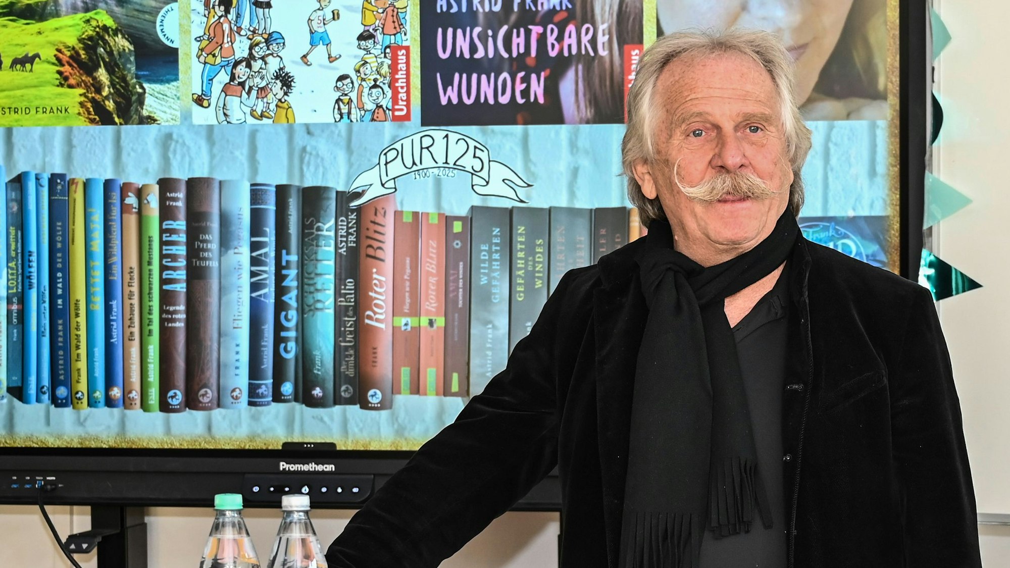 Henning Krautmacher steht vor einem Bücherregal in der Peter-Ustinov-Realschule in Köln-Nippes.