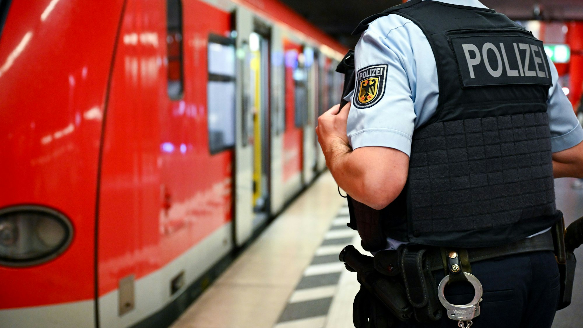 Auf dem Foto ist ein Beamter der Bundespolizei und im Hintergrund eine S-Bahn zu sehen.