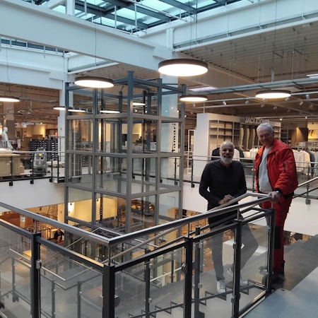 Zwei Männer stehen an einer Treppe in einem Kaufhaus