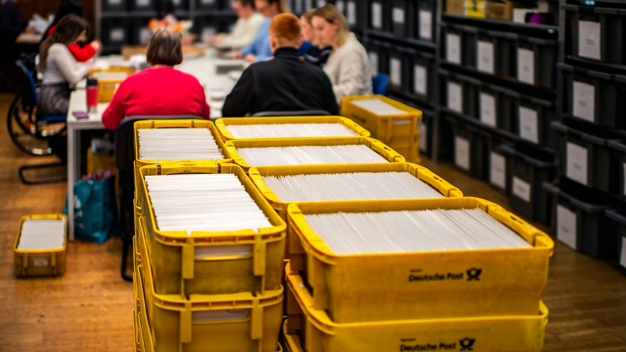 Das Bild zeigt einen Blick ins Wahlamt der Stadt Euskirchen. Im Vordergrund stehen zahlreiche gelbe Kisten mit Briefwahlunterlagen.