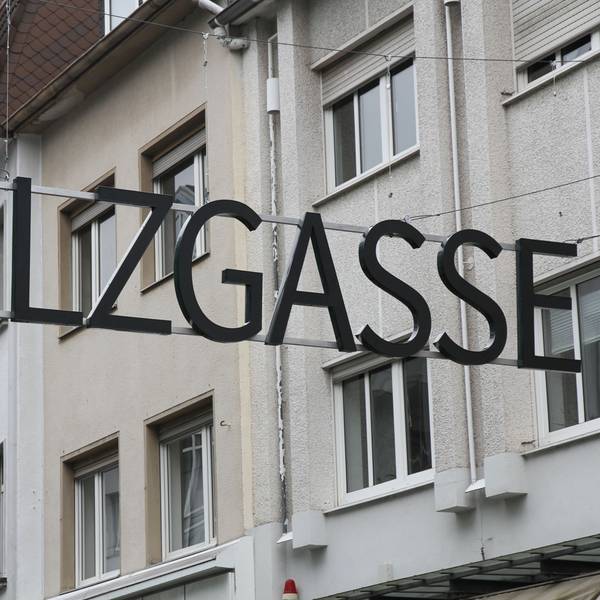Ein Schriftzug aus metallenen Großbuchstaben über einer Einkaufsstraße.